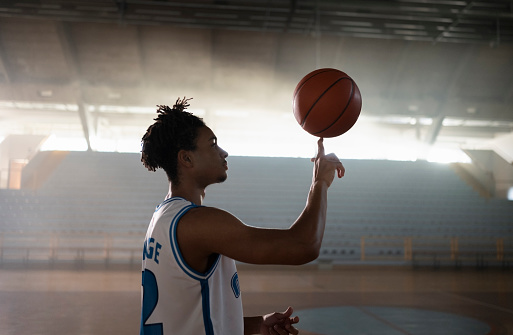 Side view of male basketball player turning basketball on his index finger during practise.