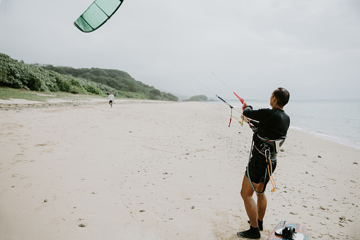 Kite surfer meticulously checks his gear, ensuring that every component is properly set up for his upcoming ride.