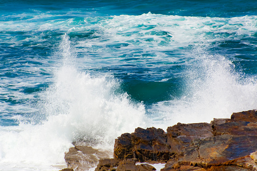 An offshore storm sends high, heavy, windswept ocean surf/breakers crashing up and over the coastal shoreline rocks at Peggy's Cove, Nova Scotia, Canada. Peggy's Cove lighthouse is in the background. Canon 5D Mark III.