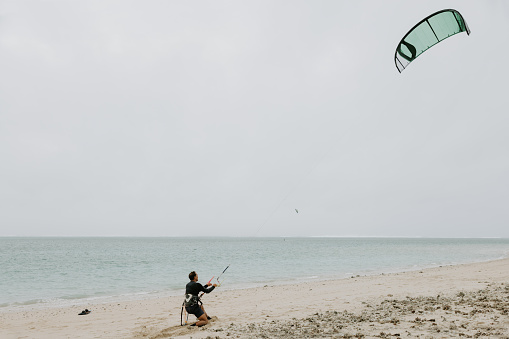 A kite surfer checking the wind and equipment, before hitting the water and waves at the beach.