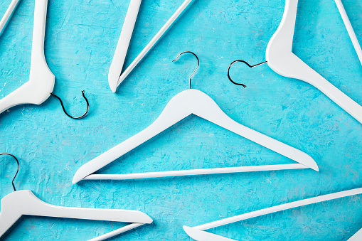 Fashion collection concept. White wooden hangers, a flat lay layout on blue. Shopping background, abstract design