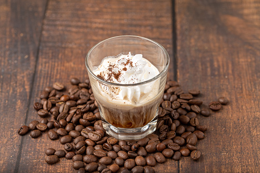 Hot espresso con panna in glass cup on wooden table