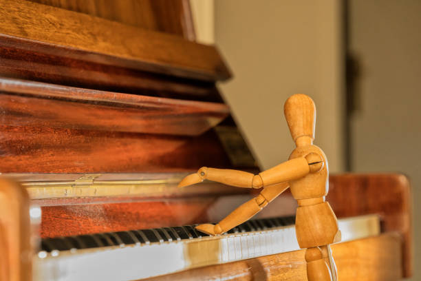 istock Wooden mannequin plays console piano. 1629169993