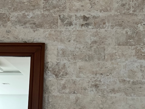 Mirror with wooden frame on travertine stone wall