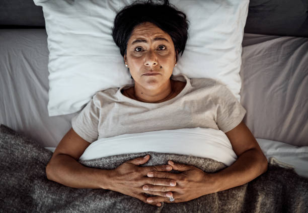 insomnio, retrato y mujer mayor en la cama desde arriba con menopausia, ansiedad o estrés en su hogar. vista superior, cara y mujer anciana en un dormitorio con depresión, trauma o crisis de salud mental - menopausia fotografías e imágenes de stock
