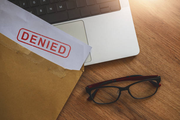 Document with denied stamp put on the laptop on wooden table,