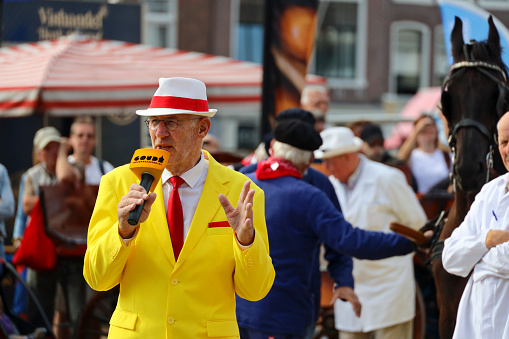 Gouda (the Netherlands), August 17th - Actors playing the traditional cheese market in Gouda with presentor with cheese microphone and yellow suit