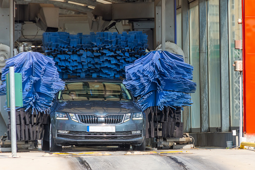 Automatic wash blue brush in action, grey car comes out ready clean