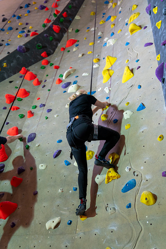 Woman climbing on the climbing wall indoor