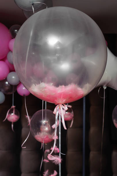 istock Transparent balloons with pink feathers inside hangs on the party 1629248701