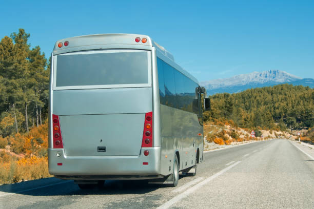 istock Silver shiny gray modern comfortable tourist bus driving through highway at bright sunny day mountains. Travel and coach tourism concept. Trip and journey by vehicle. 1629249814