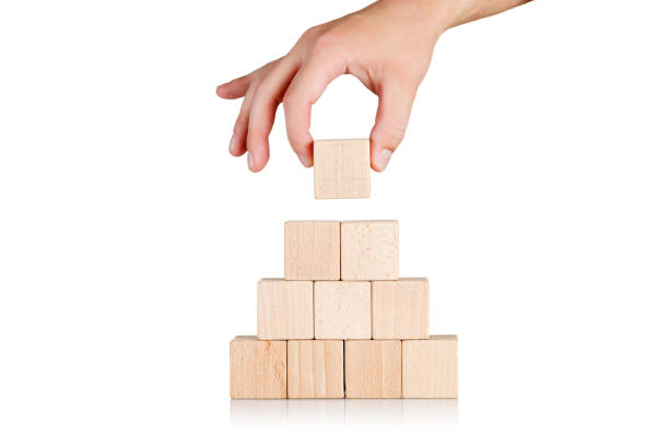istock wooden cubes in the form of a pyramid with a hand on an isolate white background 1629257609