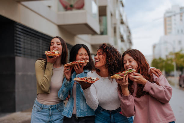 istock Friends laughing and eating pizza on the streets 1629260897