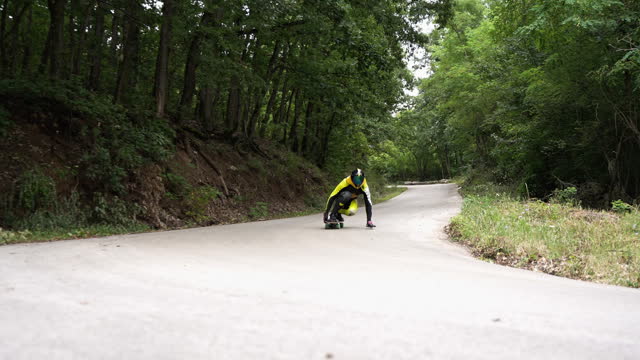 Young adult man longboarding down the road