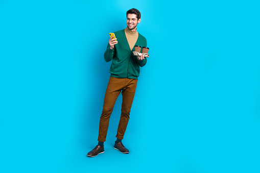 Foto de cuerpo entero de joven trabajador hombre elegante prenda de vestir navegar por teléfono café gratis mcdonalds anuncio aislado sobre fondo de color azul photo