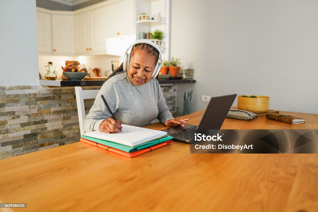 Senior african woman doing digital class webinar from home - Joyful elderly lifestyle and technology concept - Focus on face E-Learning Stock Photo