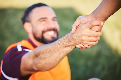 Hands, rugby and teamwork with a man helping a friend while training together on a stadium field for fitness. Sports, exercise and team building with an athlete and teammate outdoor for support