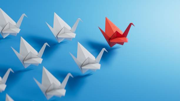 istock Boss vs Leader concept. White origami birds behind red one on blue background.3D rendering on blue background. 1629327758