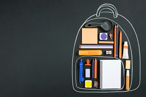 Back to school concept with chalk drawing backpack with school supplies on chalkboard