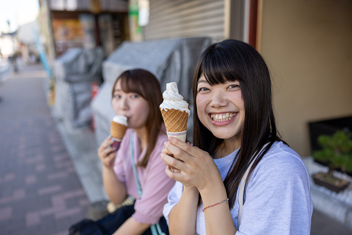 Young female friends eating ice cream in traditional Japanese town