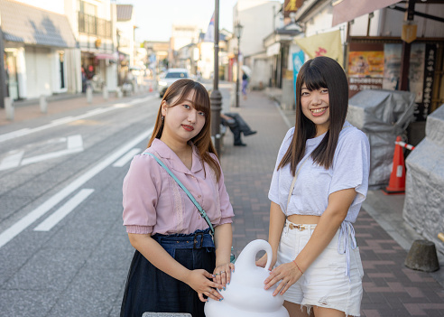 Portrait of young female friends visiting traditional Japanese town