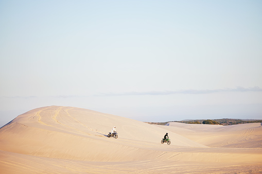 Desert, sports people and motorbike race, rally or off road marathon travel, journey and driving on competition adventure. Motorcycle speed, extreme challenge or fast racer training on sand dunes