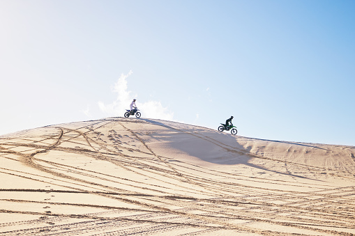 Desert, motorbike race or sports person travel, journey and driving on off road rally, outdoor challenge or bike competition. Fast motorcycle, speed or extreme athlete training on sand dunes in Dubai
