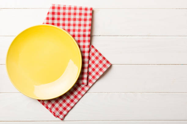 istock Top view on colored background empty round yellow plate on tablecloth for food. Empty dish on napkin with space for your design 1629393508