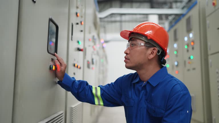 Expert electric engineer examines electric parameters on a control panel dashboard at a switchgear in factory. Focus on Control Panel operations, the engineer is engaged in a crucial task that involves Repairing, Monitoring.