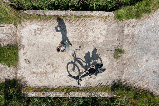 Shadow of drone pilot and his bicycle seen from straight above.