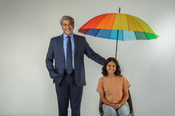 istock Businessman with daughter holding umbrella on white background 1629409336