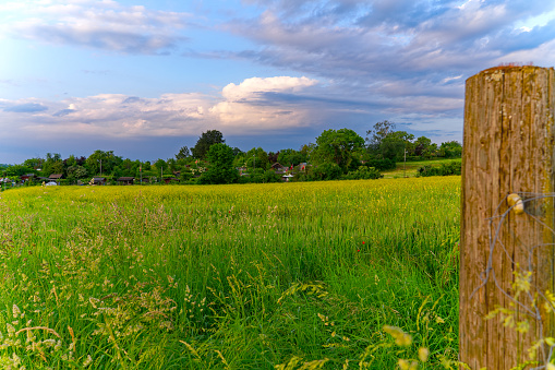 Wooden pole with scenic view of agriculture field with colorful evening sky at City of Zürich district Schwamendingen on a sunny spring day. Photo taken June 3rd, 2023, Zurich, Switzerland.