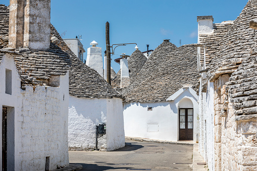 Alberobello, Italy - July 21, 2021: The Trulli of Alberobello in Apulia in Italy. These typical houses with dry stone walls and conical roofs are unique to the world and projecting this place outside of time and reality