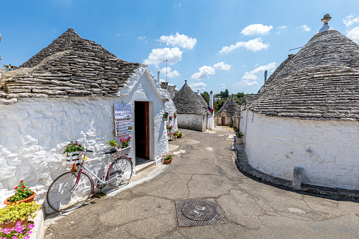 Alberobello, Italy - July 21, 2021: The Trulli of Alberobello in Apulia in Italy. These typical houses with dry stone walls and conical roofs are unique to the world and projecting this place outside of time and reality