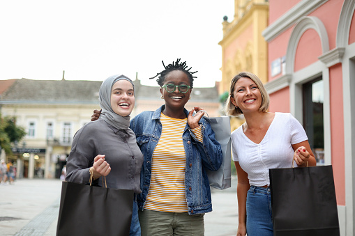 Group of three young female friends in the city. All about 20 years old, diverse women (Caucasian, Black and Middle-Eastern).