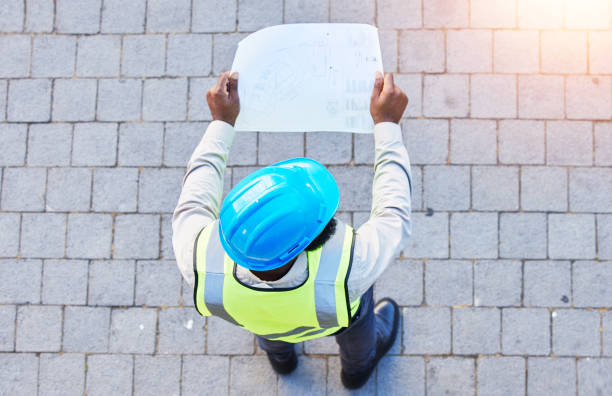 istock Construction worker, man and building inspection blueprint with industrial employee from above. African male person, professional and builder paperwork with idea and safety plan for engineer project 1629441565