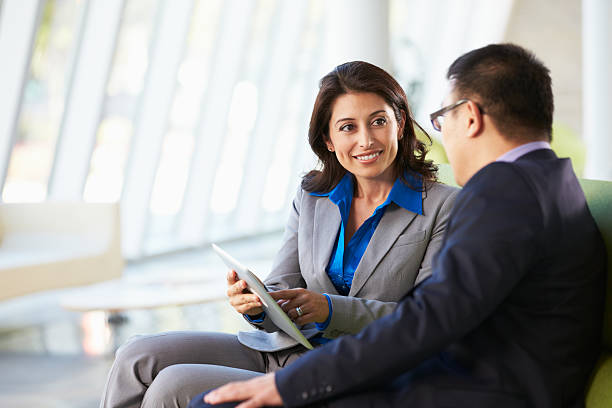 Businesspeople With Digital Tablet Sitting In Modern Office Two Businesspeople With Digital Tablet Sitting In Modern Office Reception Area business meeting 2 people stock pictures, royalty-free photos & images