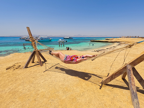 Beautiful young plus size woman lying in a hammock on the beach on the Paradise island in Egypt.