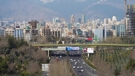Overview of the capital of Iran, Tehran with buildings and the mountains in the background and the highway with cars passing on August 16th, 2023