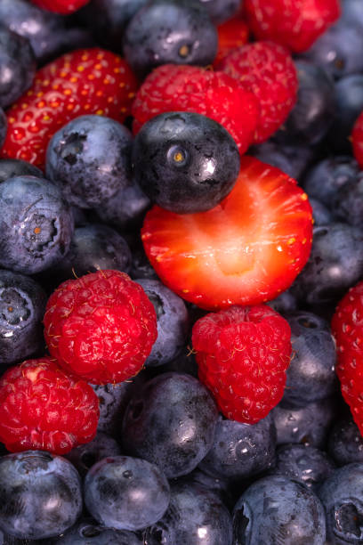 Bright background berry mix of blueberries, raspberries, strawberries, macro photography. Salad of their fresh berries, summer time. Vertical photo