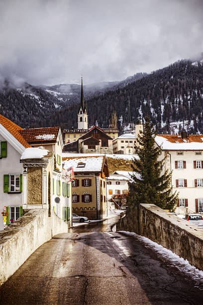 The ski resort town of Savognin tucked into the Swiss Alps near Davos and St. Moritz bathed in direct sunlight on an overcast day. Savognin is a popular destination for Swiss residents and international tourists alike. 