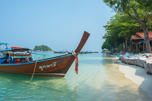 Ko Lipe, Thailand - April 11, 2023: a long-tail boat at Sunrise beach at high tide.