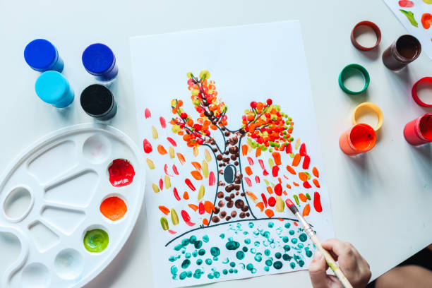 istock Child paints a tree with autumn leaves, art concept 1629554097