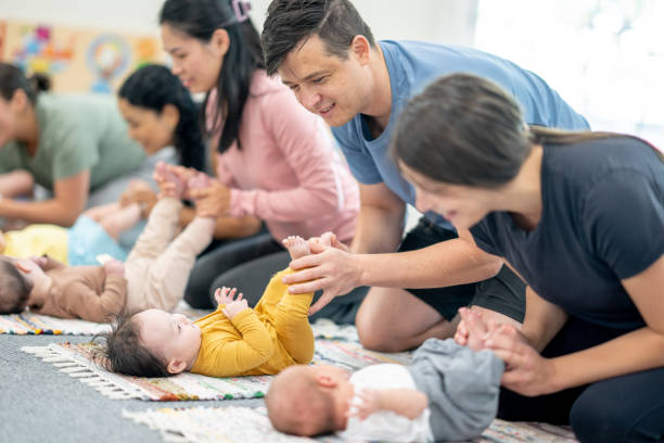 Infant Massage Class A small group of new parents sit on the floor with their babies as they participate together in an infant massage class.  They are each dressed comfortably and are engaged wth their babies. asian baby massage stock pictures, royalty-free photos & images