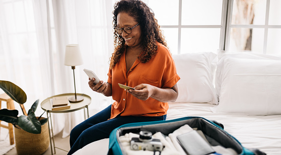 Senior traveler making online payments for a hotel stay, using the pensioner benefits on her credit card. Mature woman getting ready to start her vacation and enjoy some leisure time post retirement.