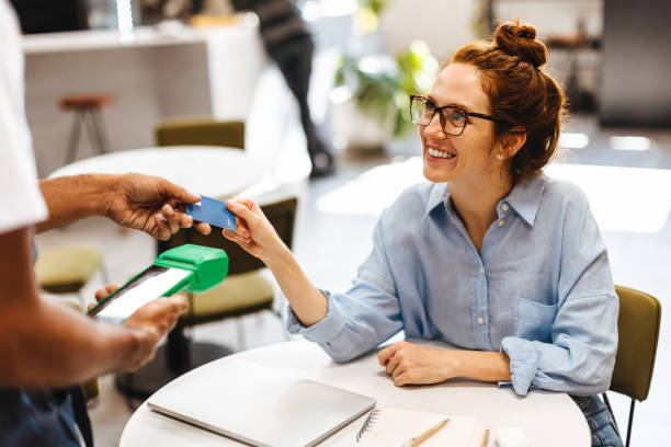 istock Female customer paying her bill with a credit card in a cafe 1629590061