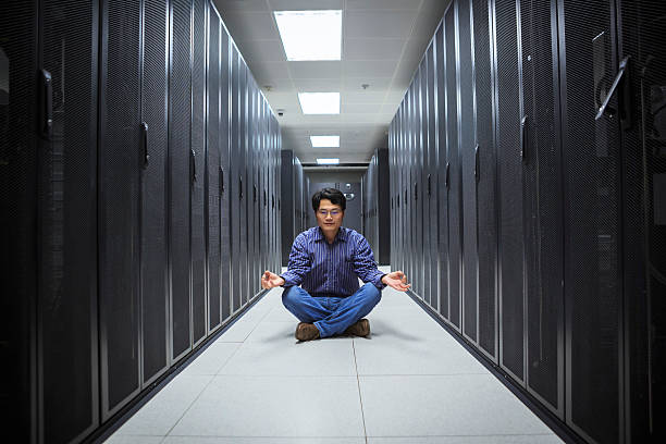 A business man doing yoga in the network server room 
