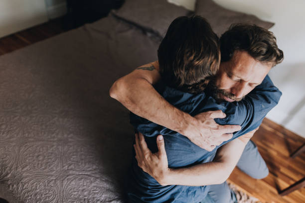 Father and son embracing in bed at home Father and son embracing in bed at home fathers day sad stock pictures, royalty-free photos & images Father and son embracing in bed at home Father and son embracing in bed at home fathers day sad stock pictures, royalty-free photos & images