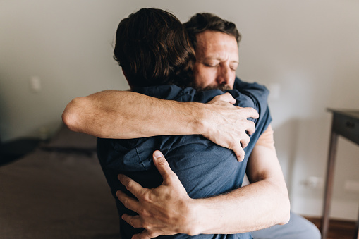 Father and son embracing at home