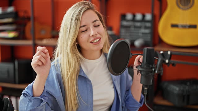 Young blonde woman musician smiling confident singing song at music studio